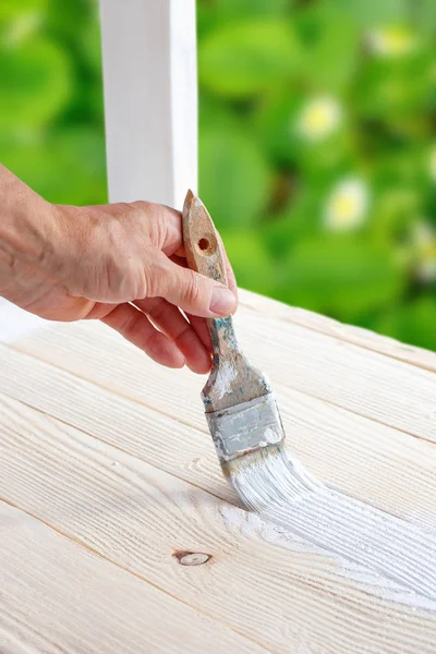 Trabajador pintura muebles de madera blanca al aire libre . — Foto de Stock