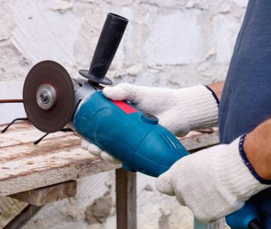 İşçi, evin arka bahçesinde elektrikli aletler, çekiç ve kerpetenle tamirat yapıyor..  