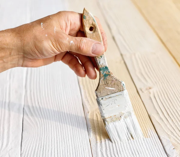 Trabajador pintura muebles de madera blanca al aire libre . — Foto de Stock