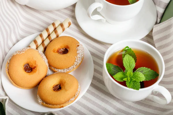 Beyaz ahşap masada lezzetli kurabiyelerle iki fincan sıcak çay. — Stok fotoğraf