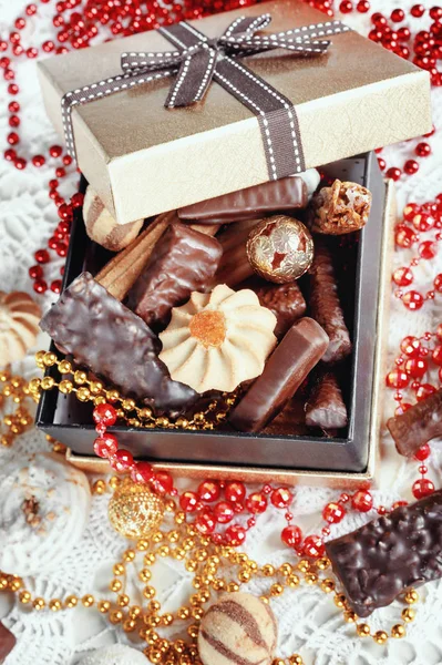 Scatola d'oro di cioccolatini, biscotti e biscotti sulla tavola festiva — Foto Stock