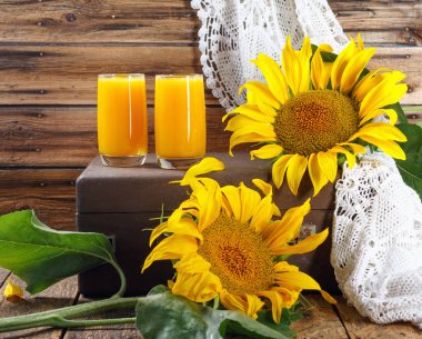 Eski ahşap duvarda ayçiçeği dalları ile taze kabak ve portakal suyu 