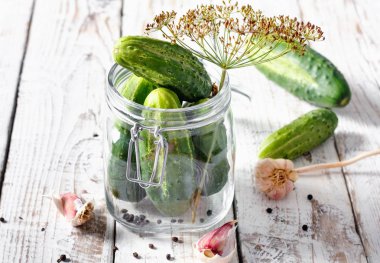 Masa üzerinde dereotu ve sarımsak ile cam kavanoz içinde korunmuş salatalık 