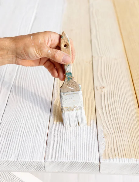 Trabajador pintura muebles de madera blanca al aire libre . — Foto de Stock