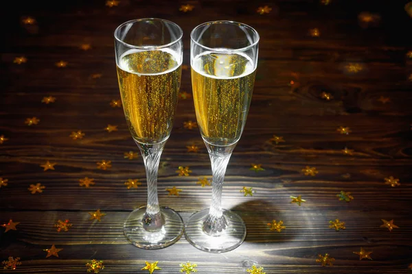 Two glasses of champagne on wooden table in New Year's Eve with bright glitter — Stock Photo, Image