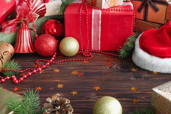 Geschenkschachteln mit Perlen, Spielzeug und Weihnachtsmann-Hut auf einem Holztisch — Stockfoto