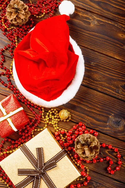 Geschenkschachteln mit Perlen, Spielzeug und Weihnachtsmann-Hut auf einem Holztisch — Stockfoto