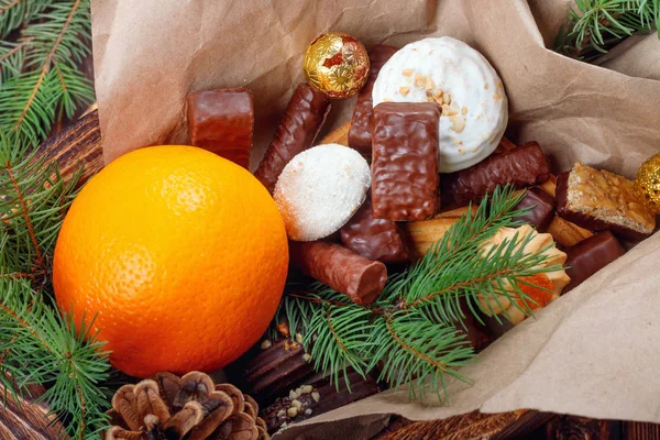 Köstliche Süßigkeiten, Pralinen, Kekse und Orangen für Geschenke in Holzkiste — Stockfoto