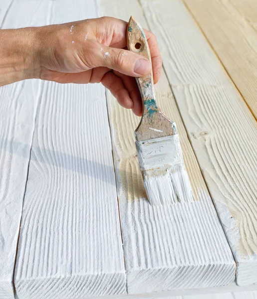 Trabajador pintura muebles de madera blanca al aire libre . — Foto de Stock