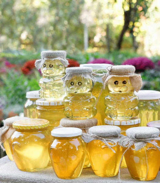 Surtido de tarros de miel en el puesto de mercado. Venta de miel natural en feria al aire libre . — Foto de Stock