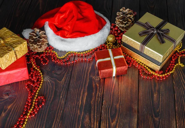 Cajas de regalo con cuentas, juguetes y sombrero de Santa Claus en mesa de madera vintage —  Fotos de Stock