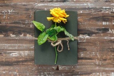 Bir buket güzel sarı güller ve ahşap arka planda eski moda kitaplar. Kutlama ya da tatil davetiyesi