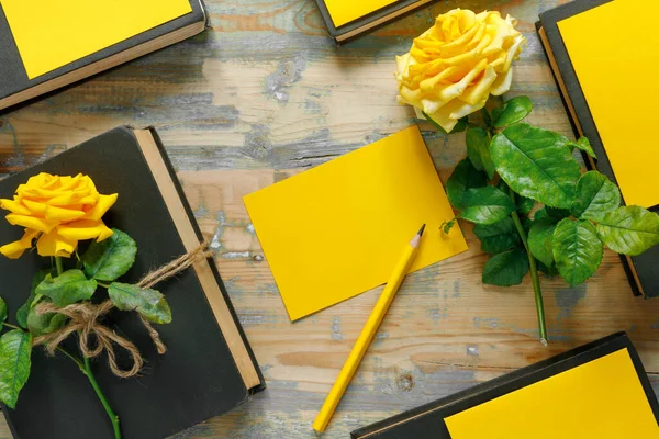 一束美丽的黄色玫瑰和一堆木制背景的书 向假日表示祝贺或邀请 — 图库照片