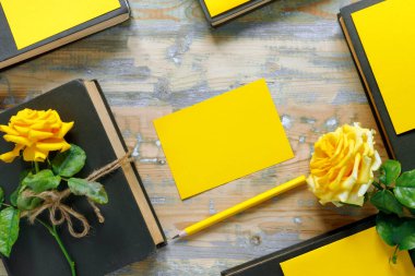 Bir buket güzel sarı gül ve ahşap arka planda bir yığın kitap. Kutlama ya da tatil davetiyesi