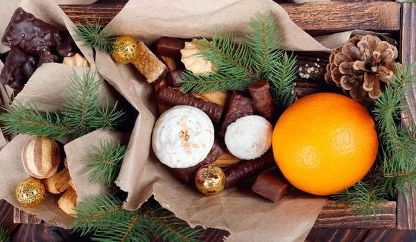 モミの枝を持つヴィンテージテーブル上の木製の箱の贈り物のためのおいしいお菓子 チョコレート クッキー オレンジ — ストック写真
