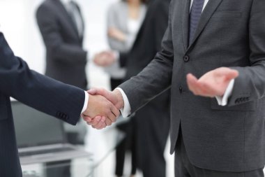 İş ortakları iş yerlerindeki iş eşyalarının üzerinden el sıkışıyor