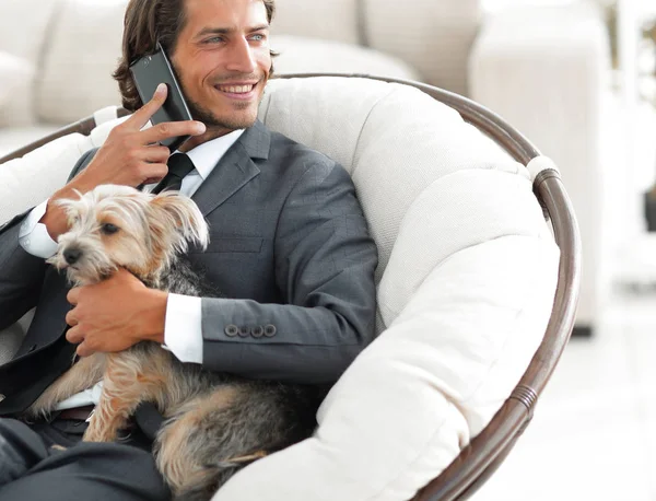 successful businessman holds his dog and pet and talks on the smartphone