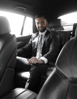 bir arabanın arka koltuğunda oturan işadamı