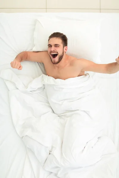 Vista dall'alto. felice uomo svegliarsi in un letto comodo — Foto Stock