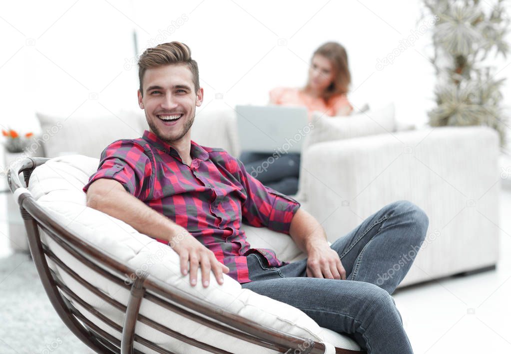 smiling young male sitting in a big chair