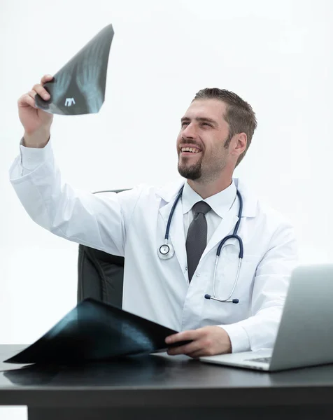 Lekarz sprawdza, czy x-ray, siedząc za biurkiem — Zdjęcie stockowe
