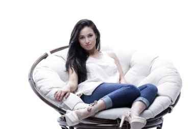 Yuvarlak, yumuşak bir sandalyede oturan modern genç kadın.