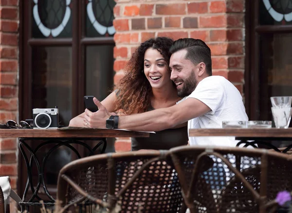 Adorável jovem casal olhando para o telefone inteligente no café — Fotografia de Stock