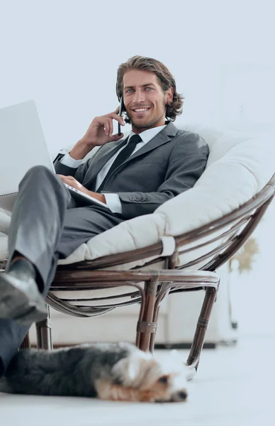 Podnikatel mluví o smartphone, sedí v křesle v jeho domě — Stock fotografie