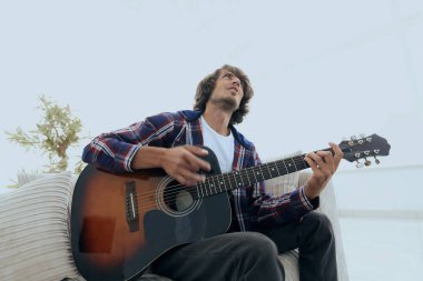 modern adam kanepede oturan gitar çalmak. bir yaşam tarzı kavramı