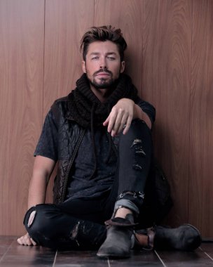 Tuğla duvarın yanında oturan yakışıklı olgun adam. Erkek modası.