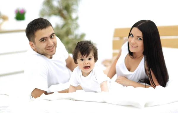 Portrait de jeune famille heureuse couchée ensemble — Photo