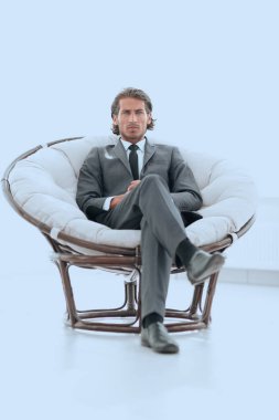Kendine güvenen işadamı büyük bir rahat sandalyede oturuyor.