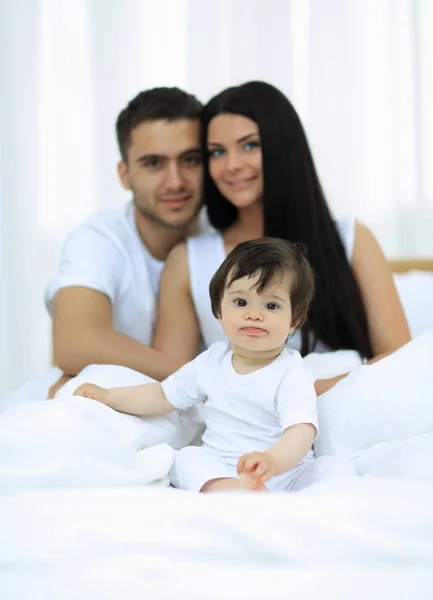 Retrato de una familia alegre sentada en la cama en casa — Foto de Stock