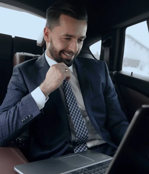 Podnikatel přečte informace o notebooku, zatímco sedí v autě — Stock fotografie
