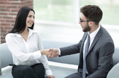 Yöneticisi ve müşteri ofis lobisinde otururken el sıkışma.