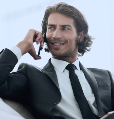 iş adamı rahat bir sandalyede otururken Smartphone'da konuşuyor.