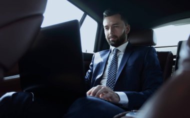 Arabada otururken diz üstü üzerinde çalışan iş adamı