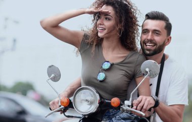 Güzel genç bir çift bir scooter sürme sırasında gülümsüyor