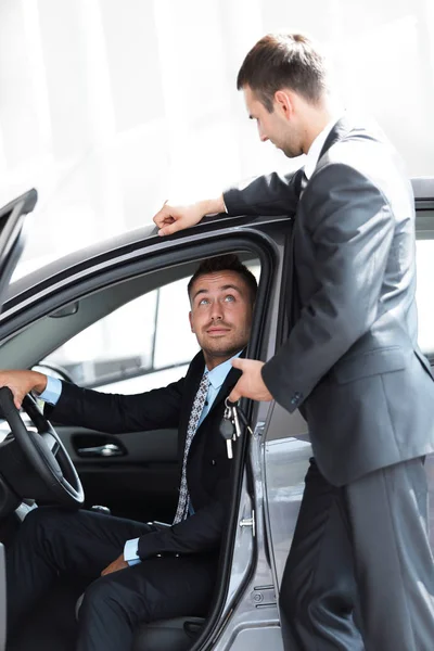 Erfolgreicher Geschäftsmann, der vom Verkäufer im Showroom die Autoschlüssel erhält — Stockfoto