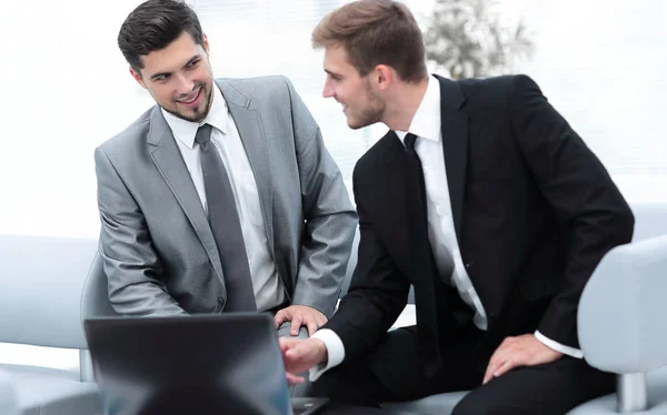 Dois colegas trabalhando em um laptop sentado no lobby do escritório . — Fotografia de Stock