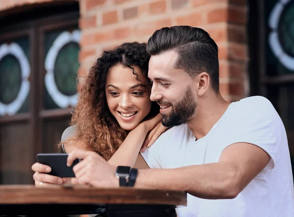 Happy älskande par som med en smartphone som sitter i terrass — Stockfoto