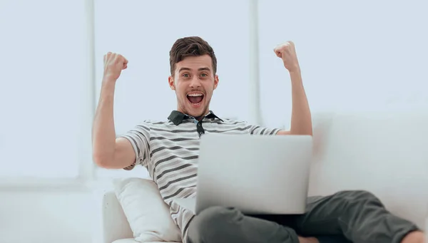 Hombre feliz con el ordenador portátil sentado en el sofá — Foto de Stock