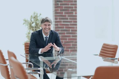 Bir boş konferans salonunda bir masada oturan proje yöneticisi