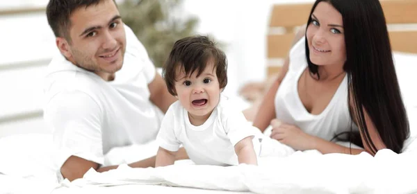 Portrait de jeune famille heureuse couchée ensemble — Photo