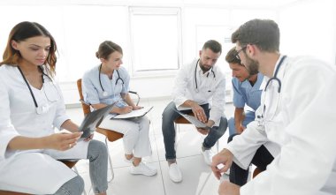 radyologlar ve cerrah hastanın bir grafisi tartışıyor