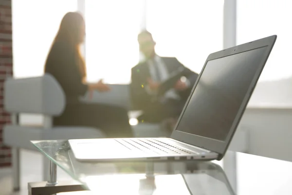 Concéntrate en el portátil sobre la mesa. Personas borrosas en el fondo . — Foto de Stock