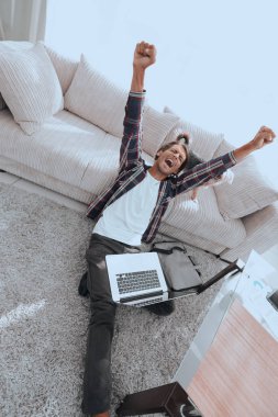 geniş oturma odasında Skordan dizüstü bilgisayar ile mutlu adam.