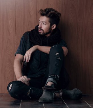 Tuğla duvarın yanında oturan yakışıklı olgun adam. Erkek modası.