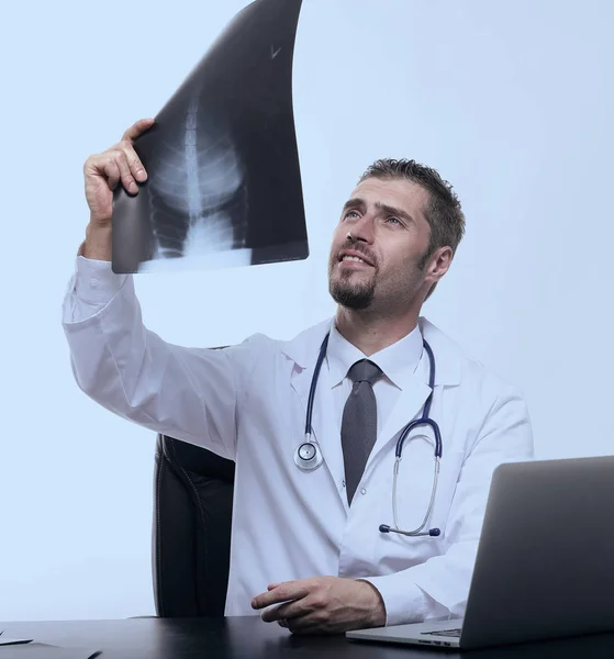 Médico examina um raio-x, sentado atrás de uma mesa — Fotografia de Stock