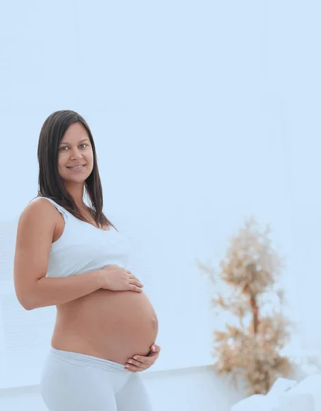 Hafif arka planda genç hamile bir kadının portresi. — Stok fotoğraf